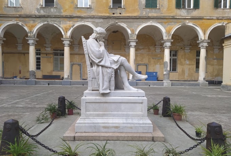 Statue av sittende Christoforo Colombo foran gammel bygning. Staden er Genova, Italia.